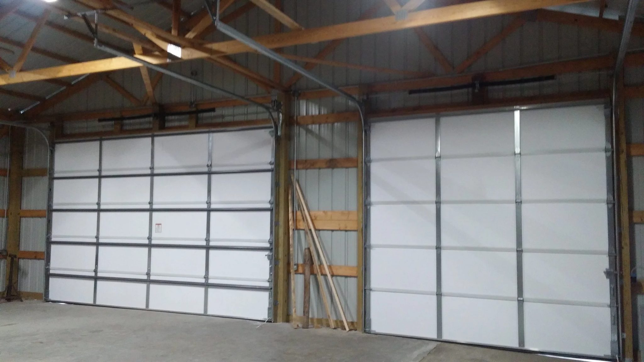 Interior view of two oversized commercial sectional doors mounted on wood-framed openings