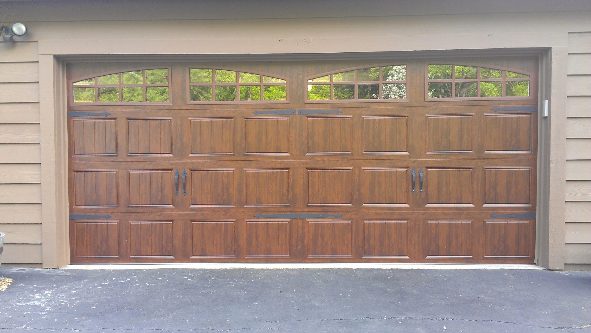Two-bay residential garage with dark wood-grain carriage doors