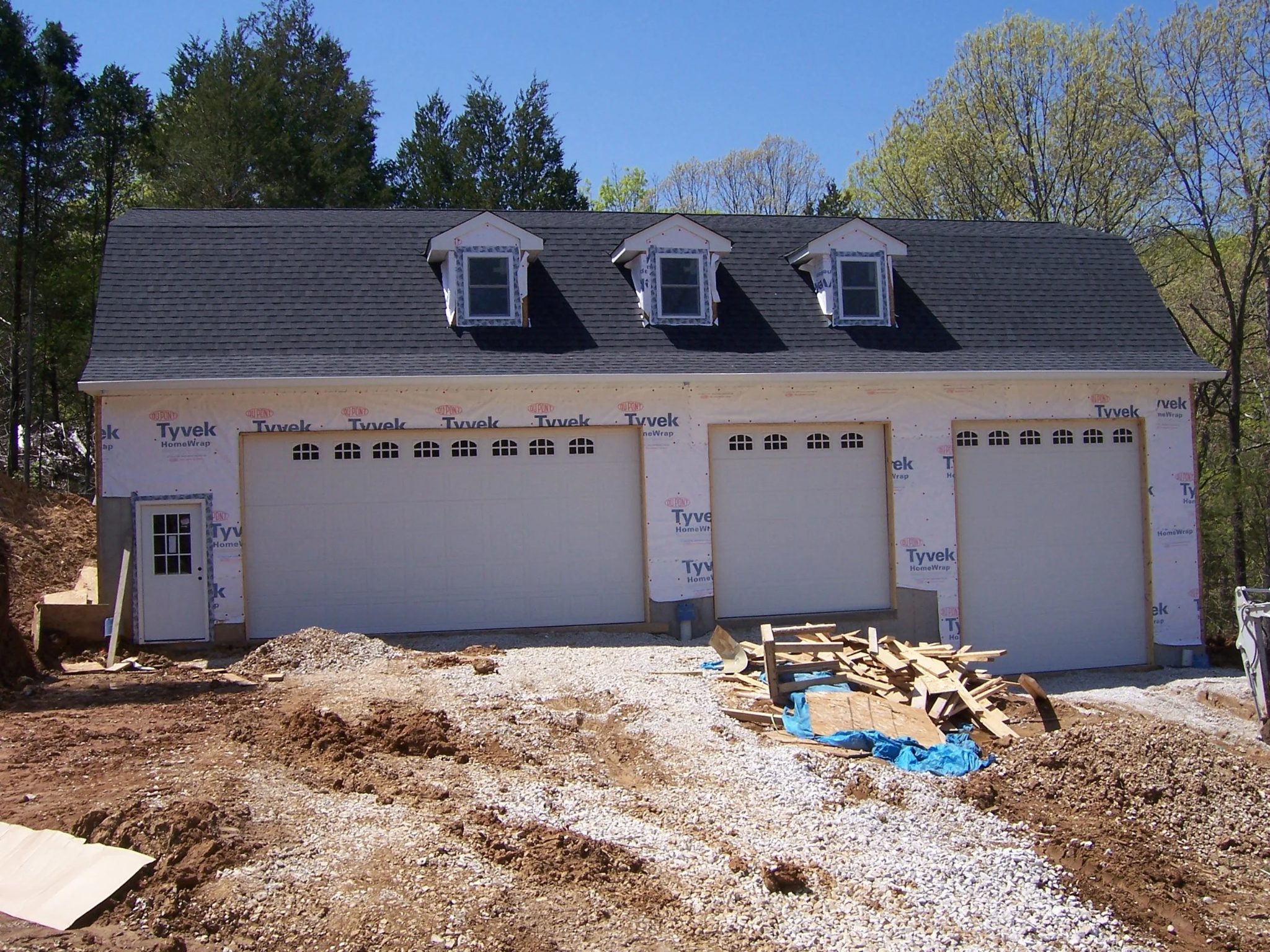 Three-bay outbuilding with carriage-window garage doors during construction