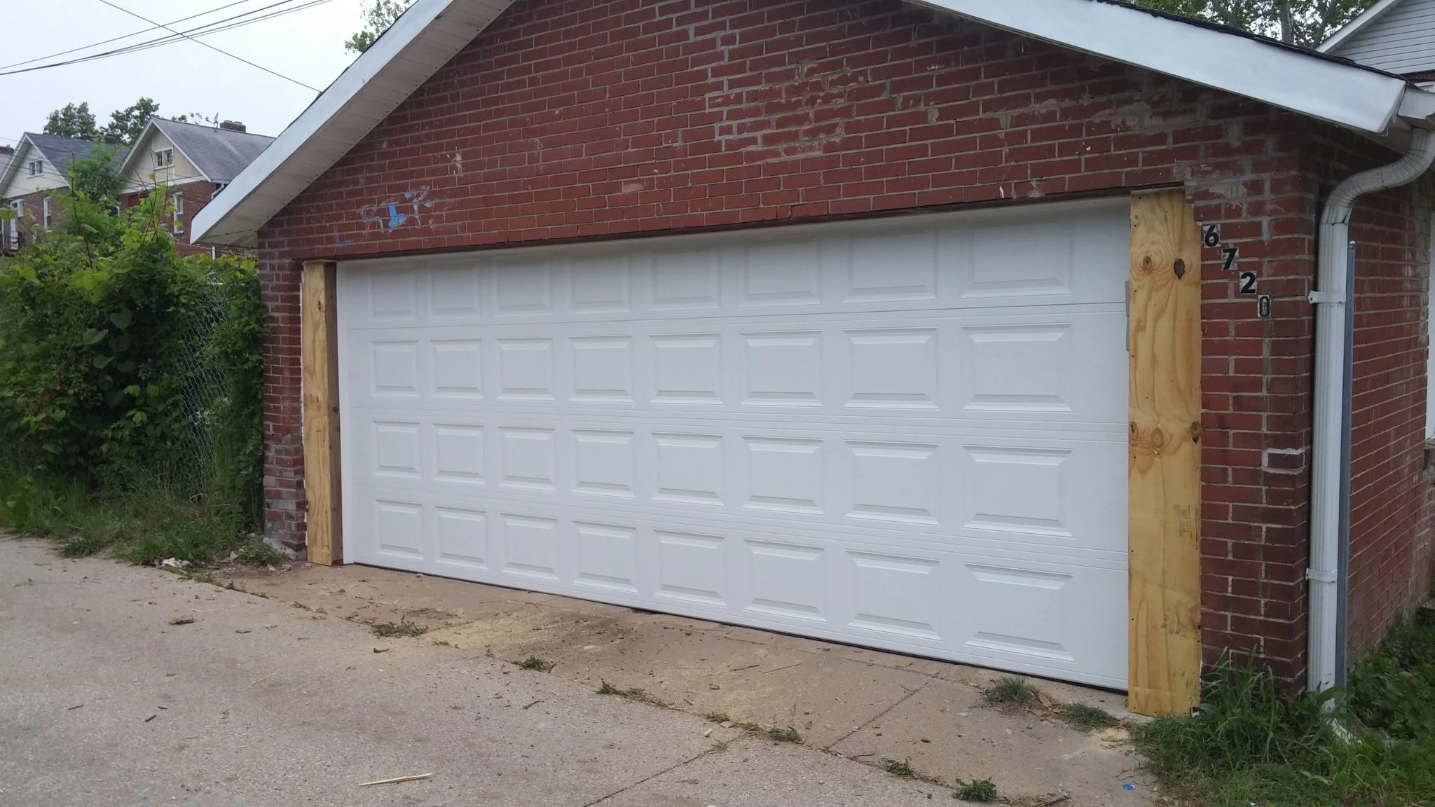 Finished brick garage with the new white raised-panel sectional door installed