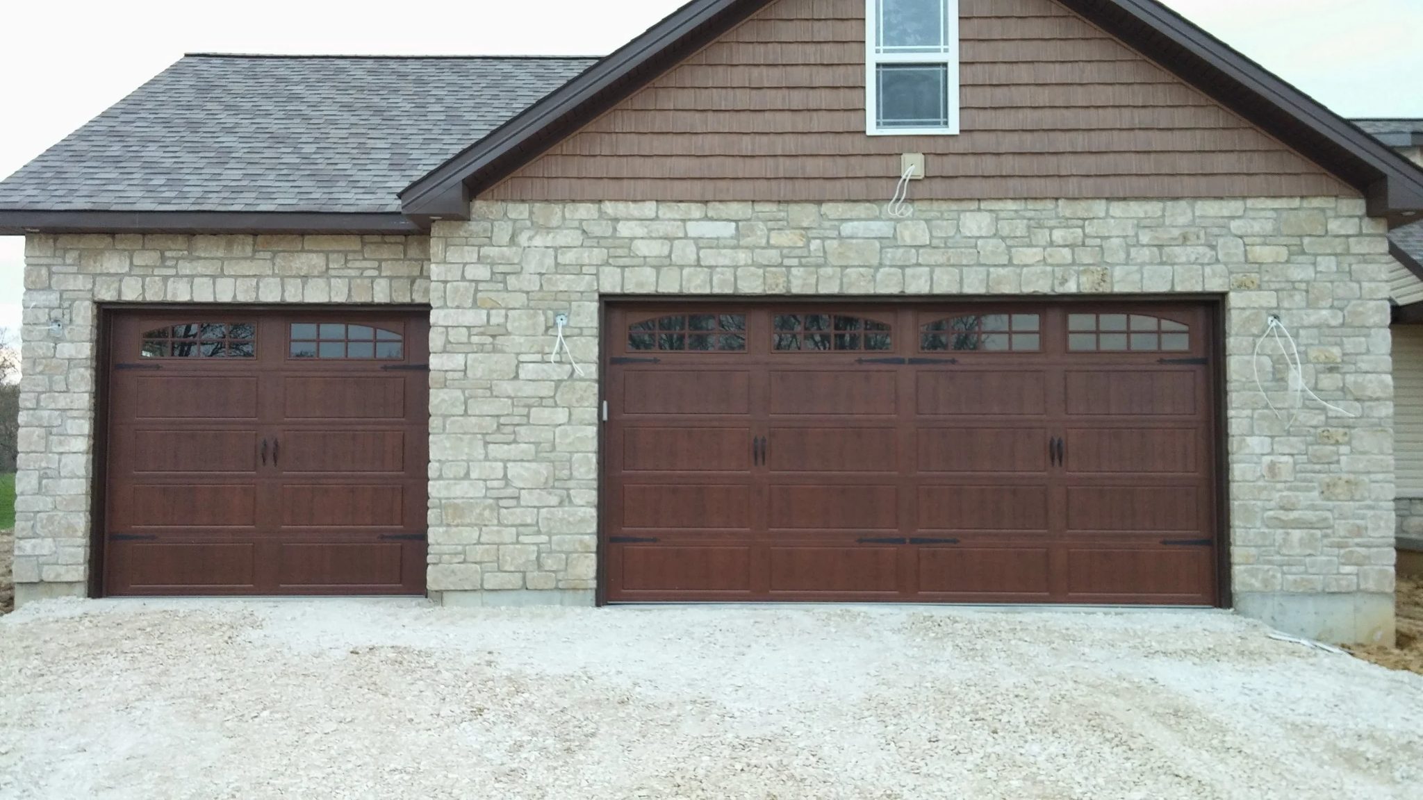 Stone-faced home with two wood-grain carriage-style garage doors