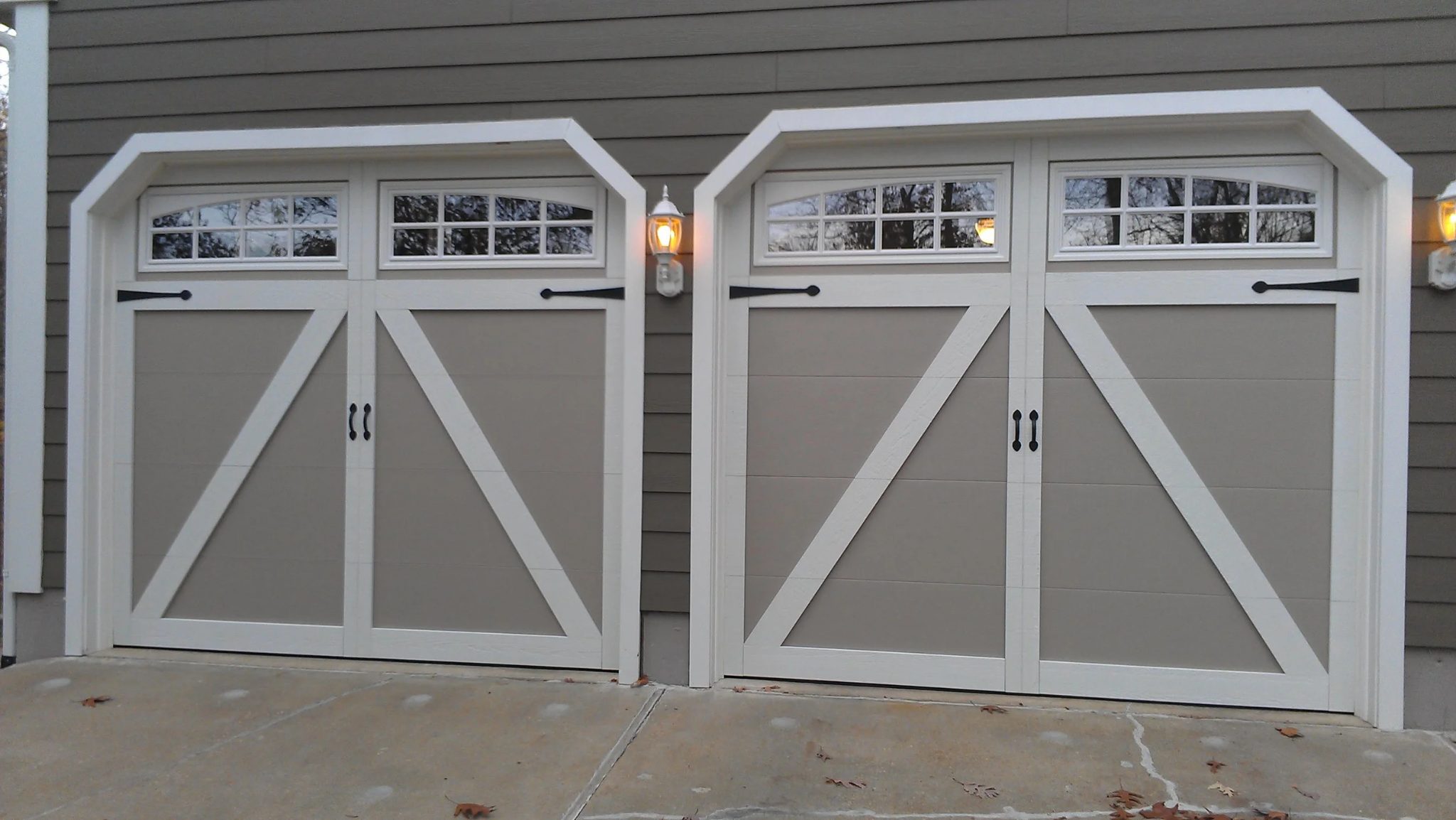 Two carriage-style garage doors with arched windows on a craftsman-style home
