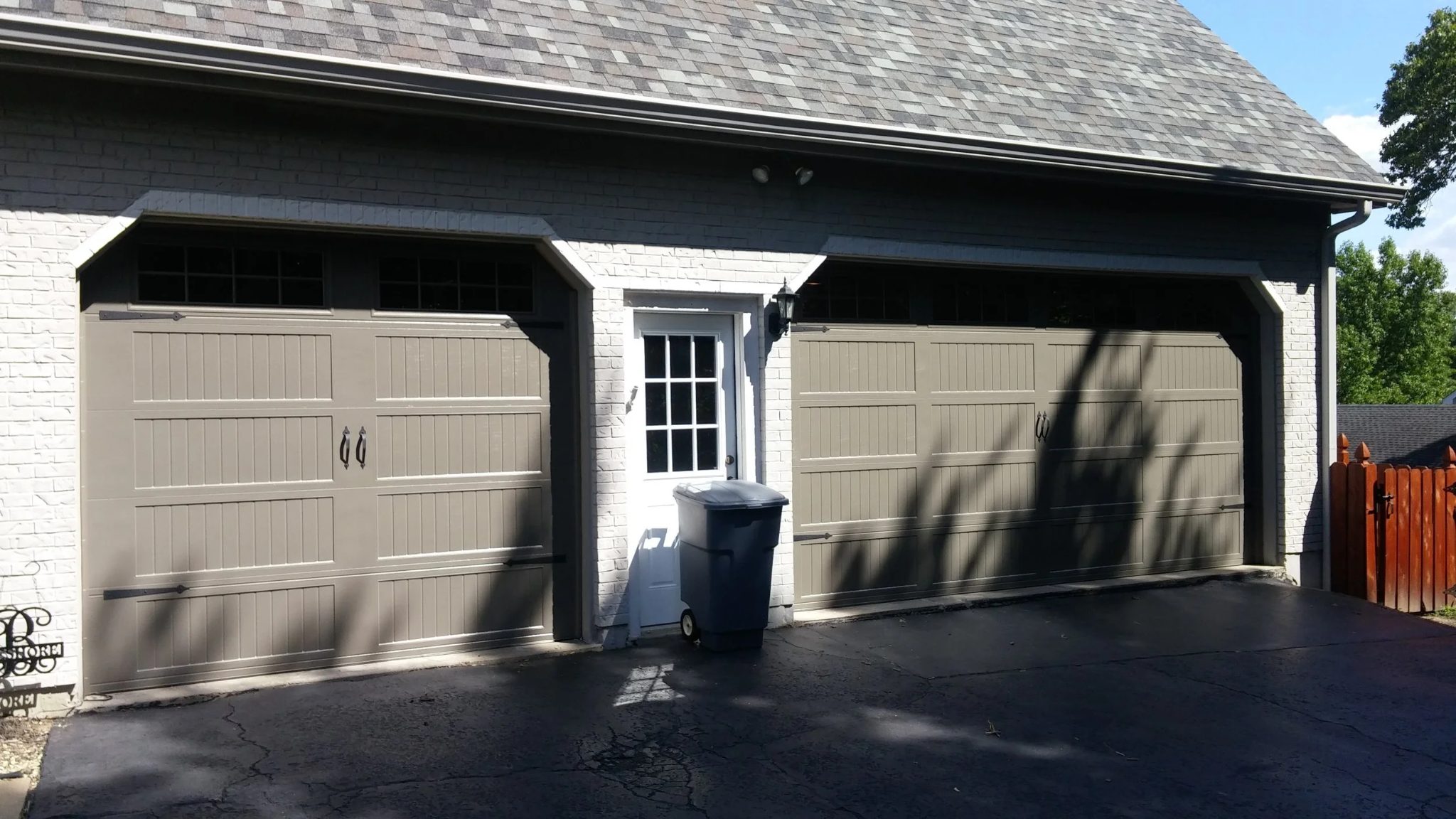 Recent install, two-bay residential garage with painted carriage-style sectional doors